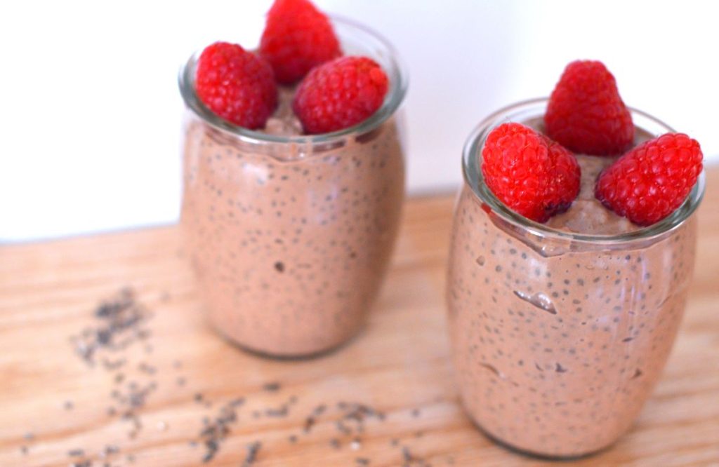 top view of two glass cups filled with chocolate chia pudding topped with raspberries