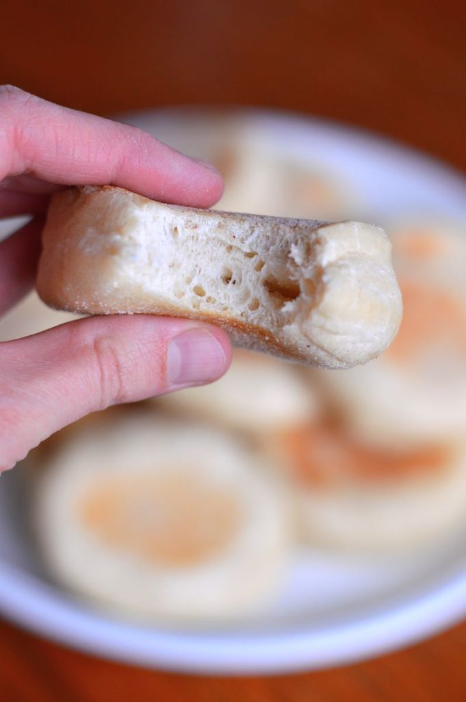 person holding english muffin that has a bite out of it