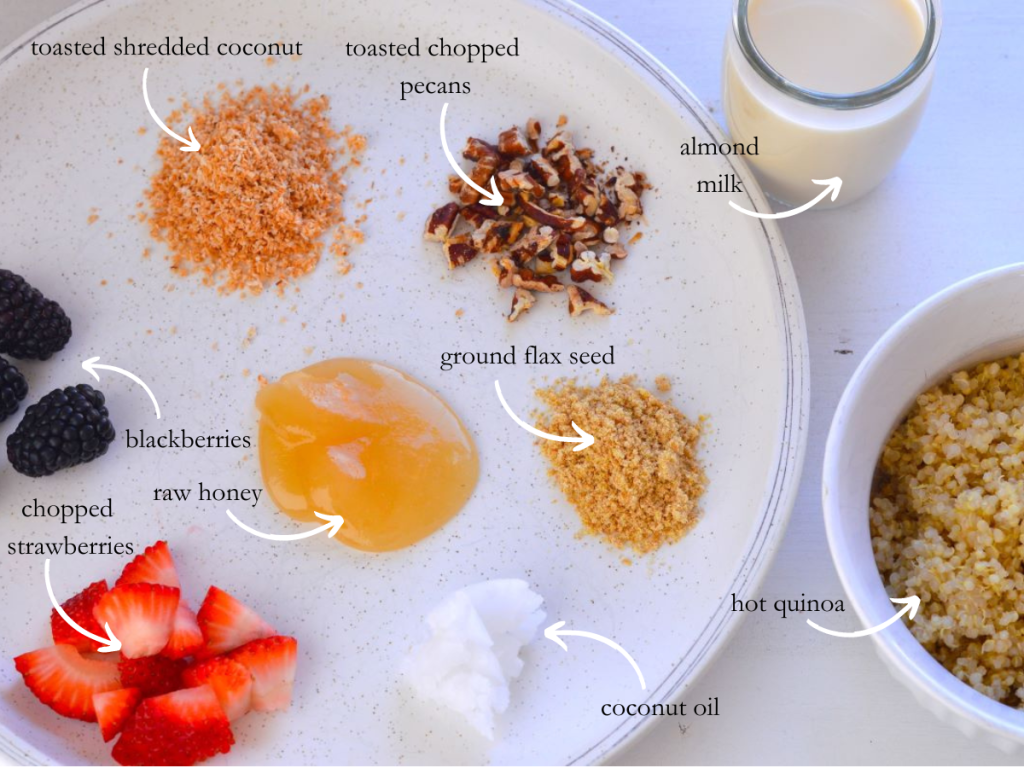 plate of toasted shredded coconut, tasted pecans, ground flax seed, blackberries, raw honey, chopped strawberries, coconut oil. Bowl of quinoa next to plate and cup of almond milk. 