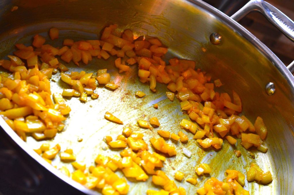 onions cooking in pan with turmeric spice