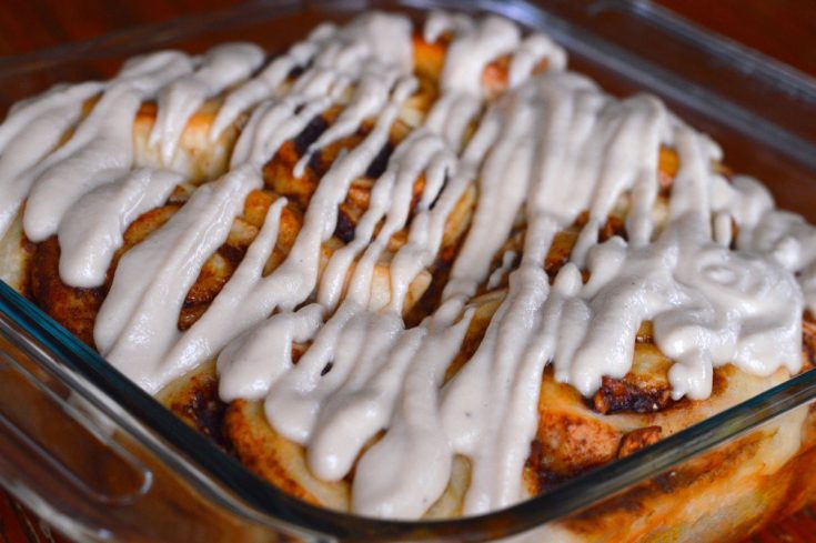 baking dish of cinnamon rolls with cashew cream drizzle on top