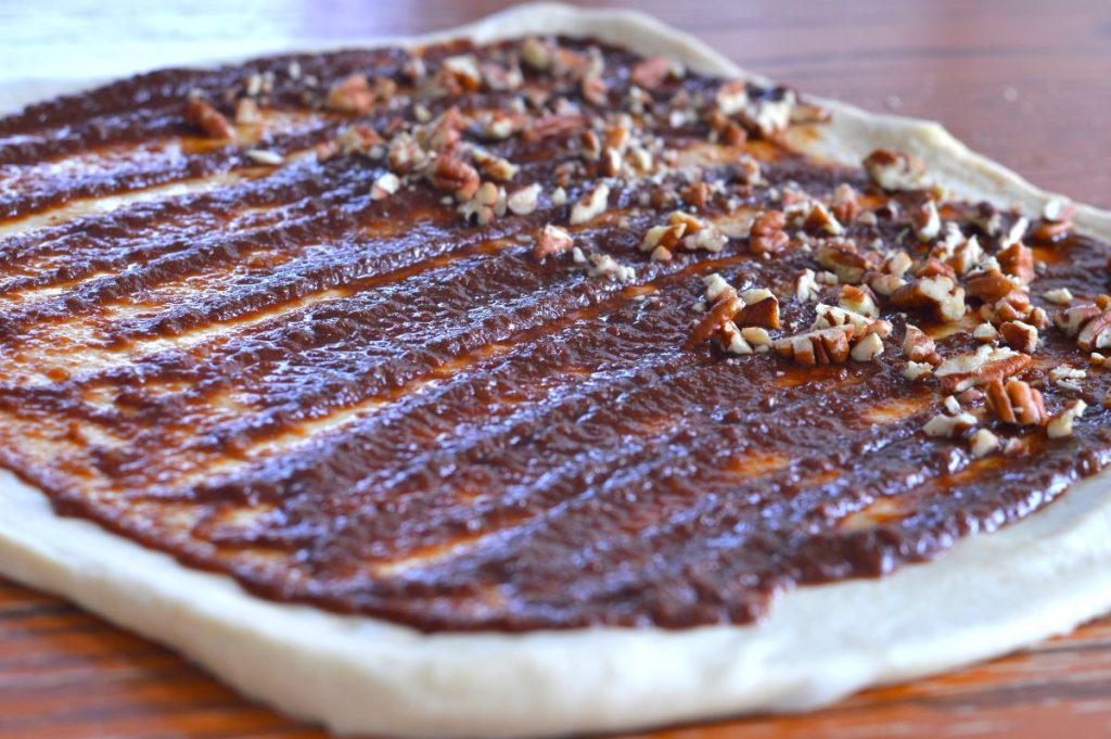 rolled dough topped with applesauce, coconut sugar, cinnamon and pecans