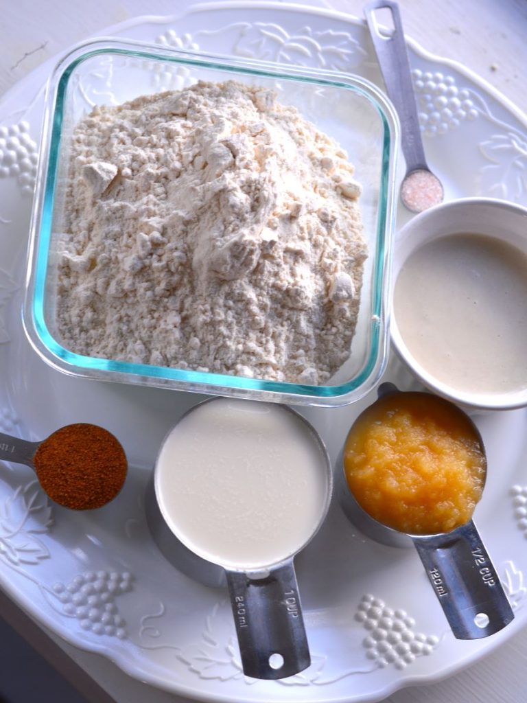 separate ingredients on a serving platter. Flour, sourdough starter, salt, applesauce, almond milk, coconut sugar.