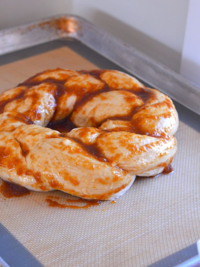 braided bread dough on cookie sheet with applesauce, coconut oil, and coconut sugar mix rubbed on
