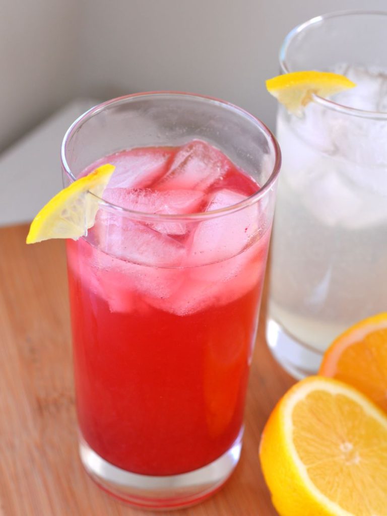 cup of ice and lemonade with slice of lemon on edge of cup