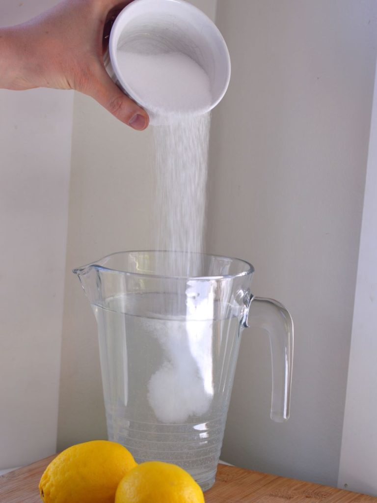 person pouring monk fruit blend into pitcher of water